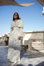 Full length view of elegant off-white modest dress with capelet design and textured vertical lines.